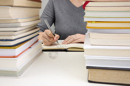 考夫曼钢笔在叠满书的课桌上写作业背景