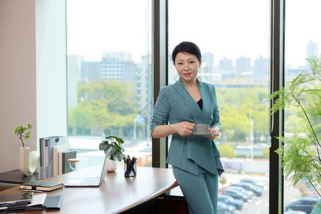 女工作素材女白领靠着办公桌喝咖啡背景