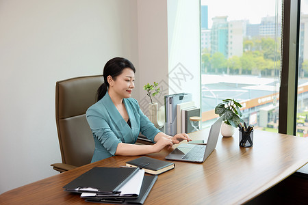 女白领坐在办公室电脑前办公背景图片