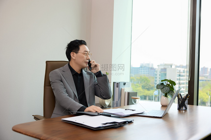 一位男白领坐在办公室打电话图片