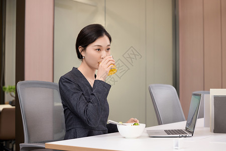 办公室里拿着橙汁的年轻女职员高清图片