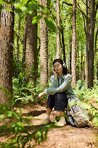 坐在森林里带耳机听歌放松的女孩高清图片