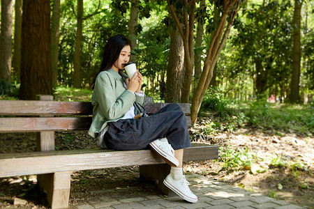 咖啡绿色坐在公园长椅上喝咖啡的女孩背景