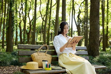 耳机女素材坐在长椅上戴着耳机听歌画画的女孩背景