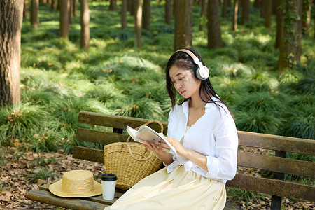 耳机女素材坐在长椅上戴着耳机听歌画画的女孩背景