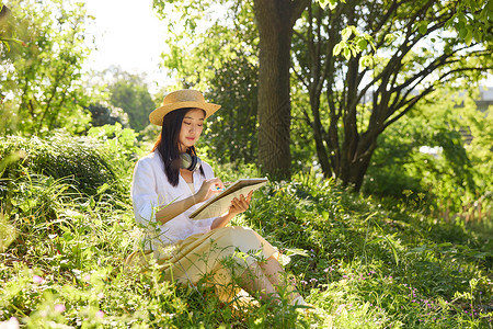坐在花中的女孩坐在草地上画画的女性背景