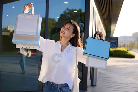 美女双手提着购物袋展示自己的购物成果高清图片