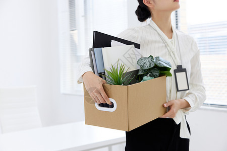 失业女性女职员抱着一箱物品离职的特写背景