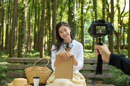 对着相机美女拿着书本对着镜头微笑背景