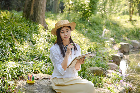 公园石墩公园里美女坐在石头上写生背景