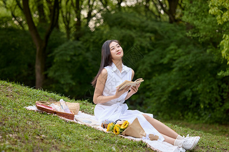 拿着书的女人户外草坪上拿着书本的美女形象背景