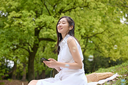 带耳机美女户外坐在草坪上带耳机听歌的美女背景