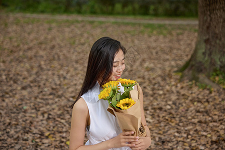 户外抱着向日葵花束的美女高清图片