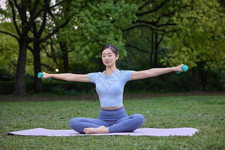 美女坐在瑜伽垫上张开双臂高清图片