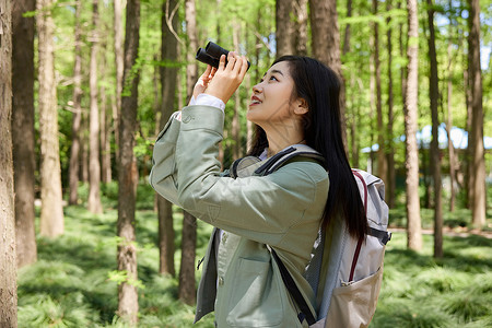 背包样机森林公园里美女用望远镜观察背景