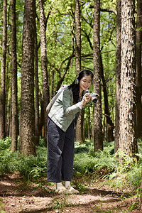 美女在森林公园用相机拍摄美景背景图片