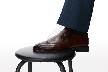 男装大促一只穿着皮鞋的脚踩在 凳子上背景