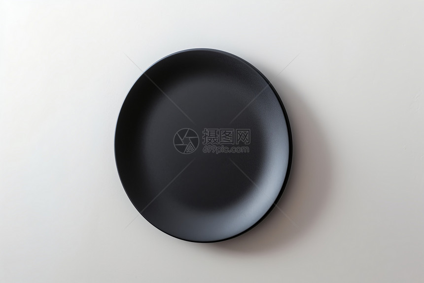 白色板上的黑色瓷碗图片