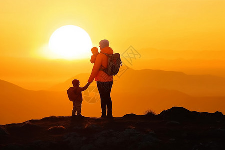 母亲带着孩子们在山顶看日落背景图片
