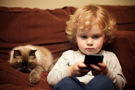 猫咪陪小男孩躺在沙发玩游戏高清图片