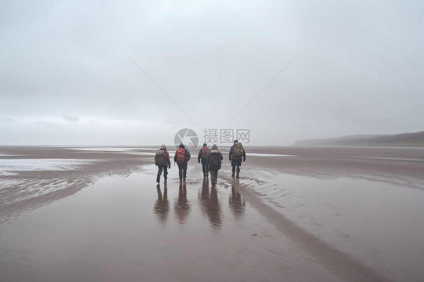 冬天一群背包客游客在沙滩上赶海图片