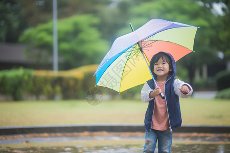雨中行走孩子撑彩虹伞的孩子背景