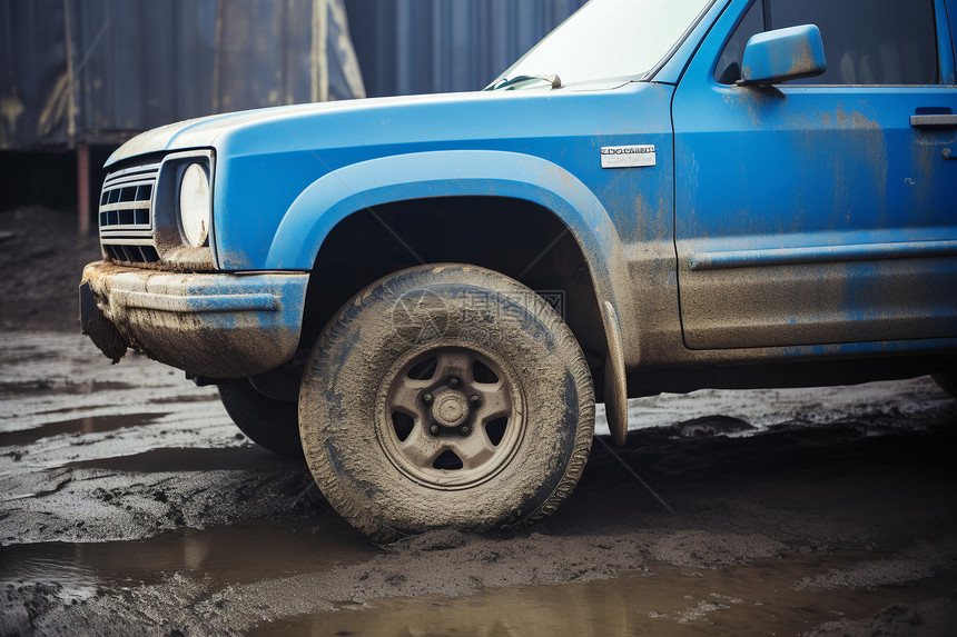 泥泞停车场中停泊的蓝色卡车图片