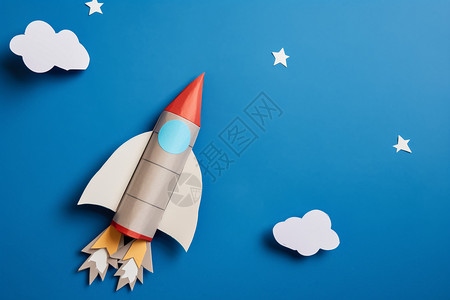 蓝天白云中飞舞的星星纸火箭背景图片