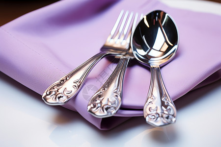 紫色餐巾上的银质餐具背景图片