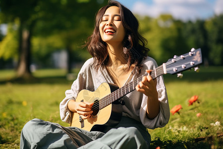 草坪上演奏吉他的年轻女子高清图片