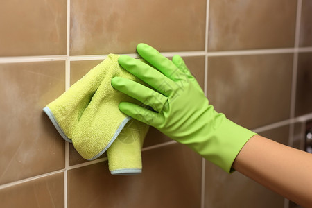 女浴室女工用抹布擦拭瓷砖墙背景