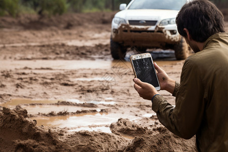 泥泞道路上手拿手机的男子图片