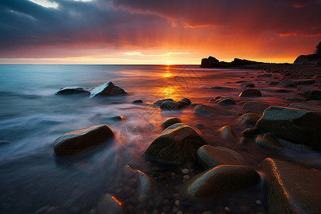 日落余晖照亮的岩滩景观高清图片