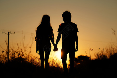 夕阳下一对手牵手的情侣背景图片